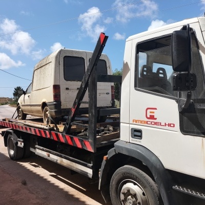 Camião de reboque branco transportando carrinha branca suja num dia claro