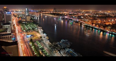 Vista noturna de área ribeirinha urbana com barcos e edifícios iluminados