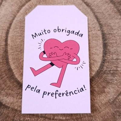 Etiqueta com coração cor-de-rosa e texto em português sobre superfície de madeira
