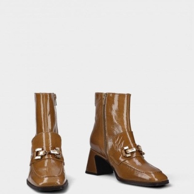 Botins castanhos brilhantes com salto e fivela metálica.