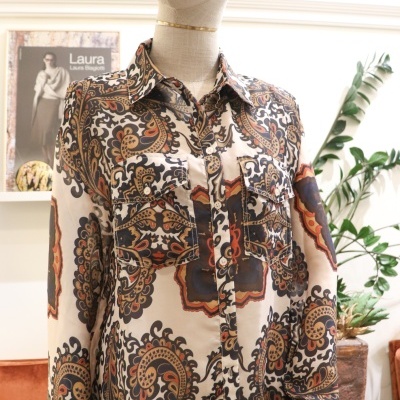 Camisa padrão paisley em manequim com planta ao fundo