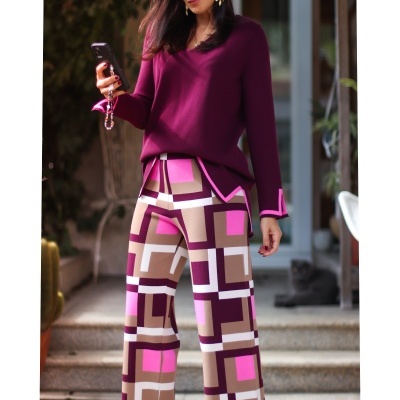 Mulher com blusa vinho e calças geométricas coloridas em ambiente exterior