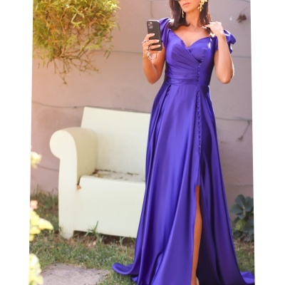 Vestido longo roxo satinado com decote em V, botões e fenda, em jardim com sofá branco