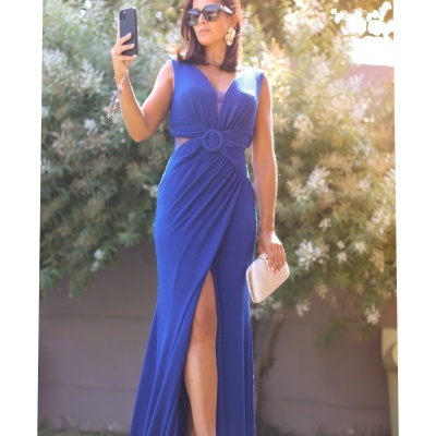 Mulher de vestido longo azul com cinto circular e abertura, a tirar selfie no jardim