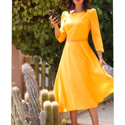 Mulher com vestido amarelo midi e óculos escuros junto a cactos e plantas