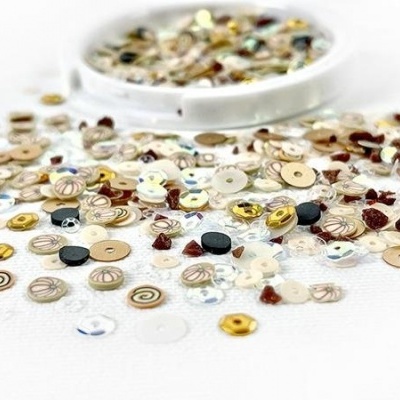 Lantejoulas coloridas espalhadas e um recipiente branco cheio delas