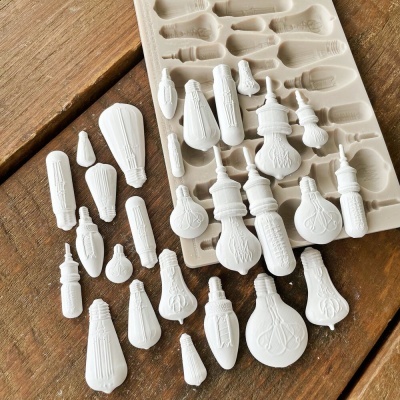 Moldes de silicone com figuras de lâmpadas em gesso branco numa superfície de madeira
