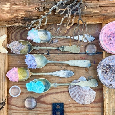 colheres com cristais coloridos e frascos de creme em madeira rústica com conchas e estrela-do-mar