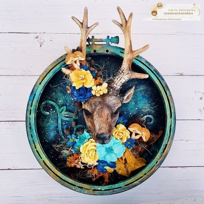 Decoração mural com cabeça de veado e flores artificiais num aro azul