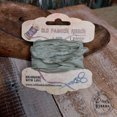 Fita verde clara de tecido enrugado em cartão branco com texto e ilustrações sobre madeira rústica