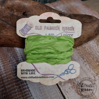 Fita verde enrolada em cartão branco com texto e ilustrações sobre madeira