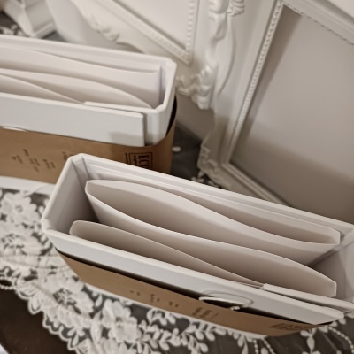 Caixas de cartão com pastas brancas em superfície com tecido branco floral