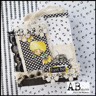 Cartão decorativo preto e branco com flores amarelas e renda, texto 'just be'.