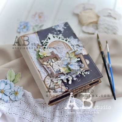 Livro decorativo com flores artificiais e recortes em papel sobre tecido branco rendado