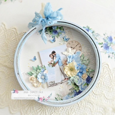 Moldura redonda azul claro com foto de casal e decoração floral azul e branca