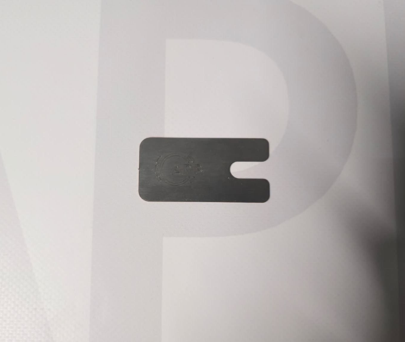 Black rectangular clip with U-shaped cutout and embossed text 'CAP' on white background with large faint letter P