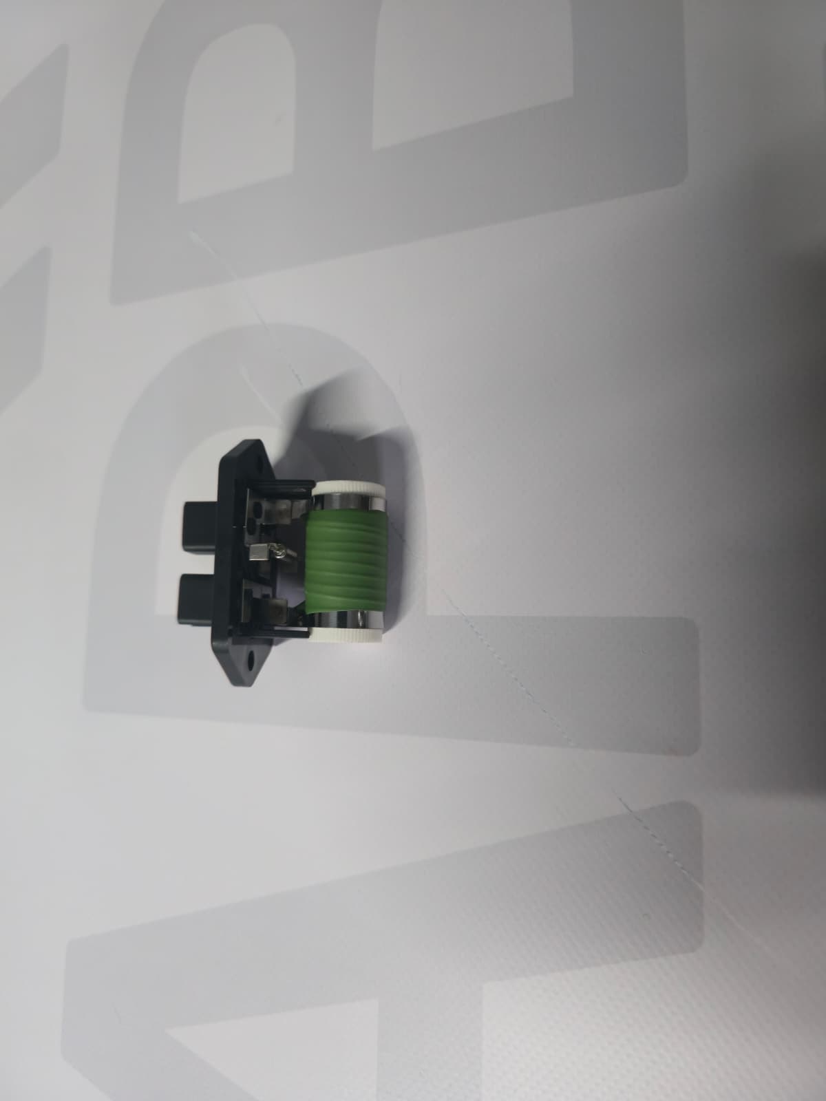 Small electrical component with black base and green cylinder on white background