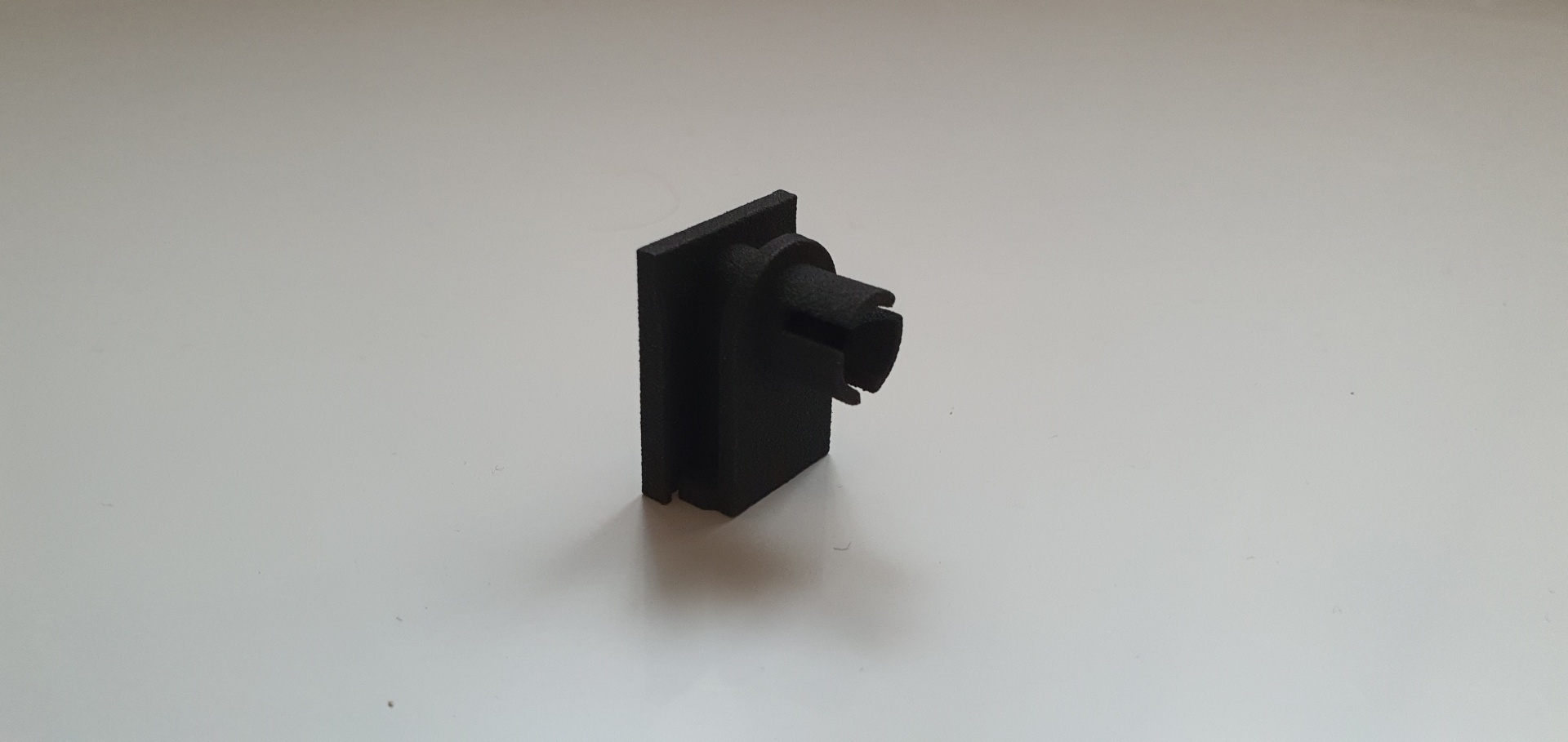 Peça pequena preta com botão em fundo branco