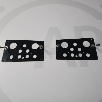 Two black metal plates with circular holes and metal pegs on a white surface