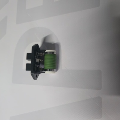 Small electrical component with black base and green cylinder on white background