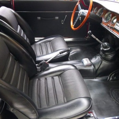 Interior de carro clássico com bancos pretos em couro e volante de madeira