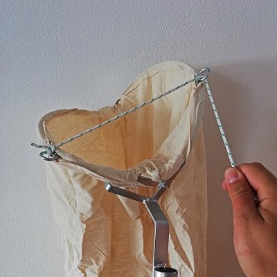 Saco de pano branco com armação metálica circular e suporte tubular