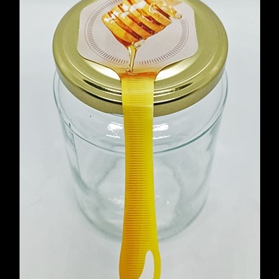 Frasco de vidro com tampa dourada e rótulo com colher de mel