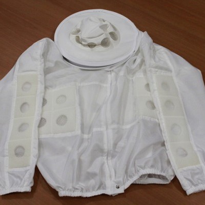 Vestuário protetor branco com chapéu sobre superfície de madeira