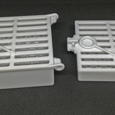 Duas caixas plásticas brancas com tampas de grade sobre superfície preta