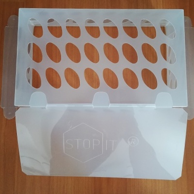 Apoio para talheres branco em plástico com recortes ovais e inscrição 'STOP IT®' sobre superfície de madeira