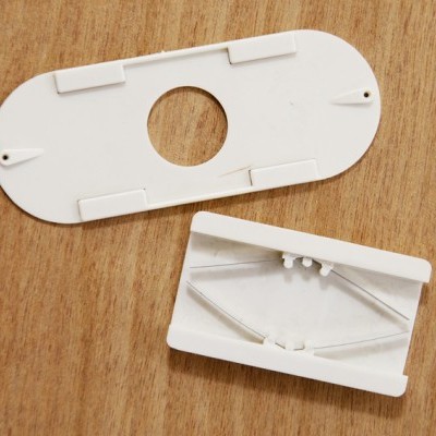 Duas peças de plástico branco com encaixes, sobre fundo de madeira clara