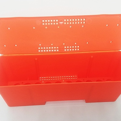caixa retangular de plástico laranja com tampa perfurada aberta
