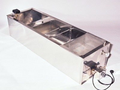 Aparelho metálico longo com divisórias internas e malha na extremidade