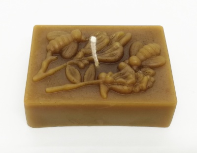 Sabonete retangular castanho com relevo de abelhas e flores e corda branca.