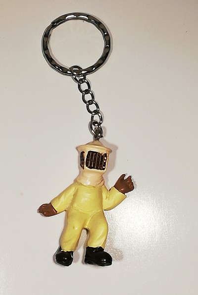 Porta-chaves com figura de personagem em fato amarelo e capacete bege