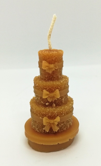 Vela castanha em formato de bolo decorativo com três andares e laços.