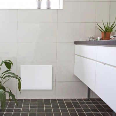 Casa de banho com armário branco, azulejos brancos e plantas em vasos.