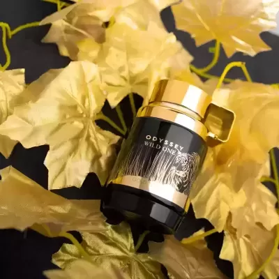 Frasco de perfume ODYSSEY WILD ONE sobre folhas douradas