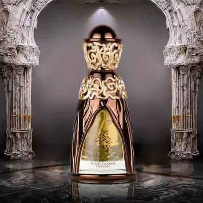 Frasco de perfume dourado Zikra com tampa decorativa em fundo cinzento e arquitetura branca