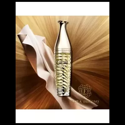 Frasco de perfume dourado e transparente sobre tecido creme e fundo dourado.