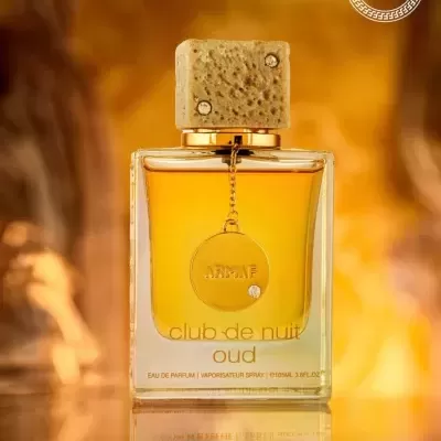 Frasco de perfume club de nuit oud da ARMAF com tampa de pedra e moeda dourada pendurada.