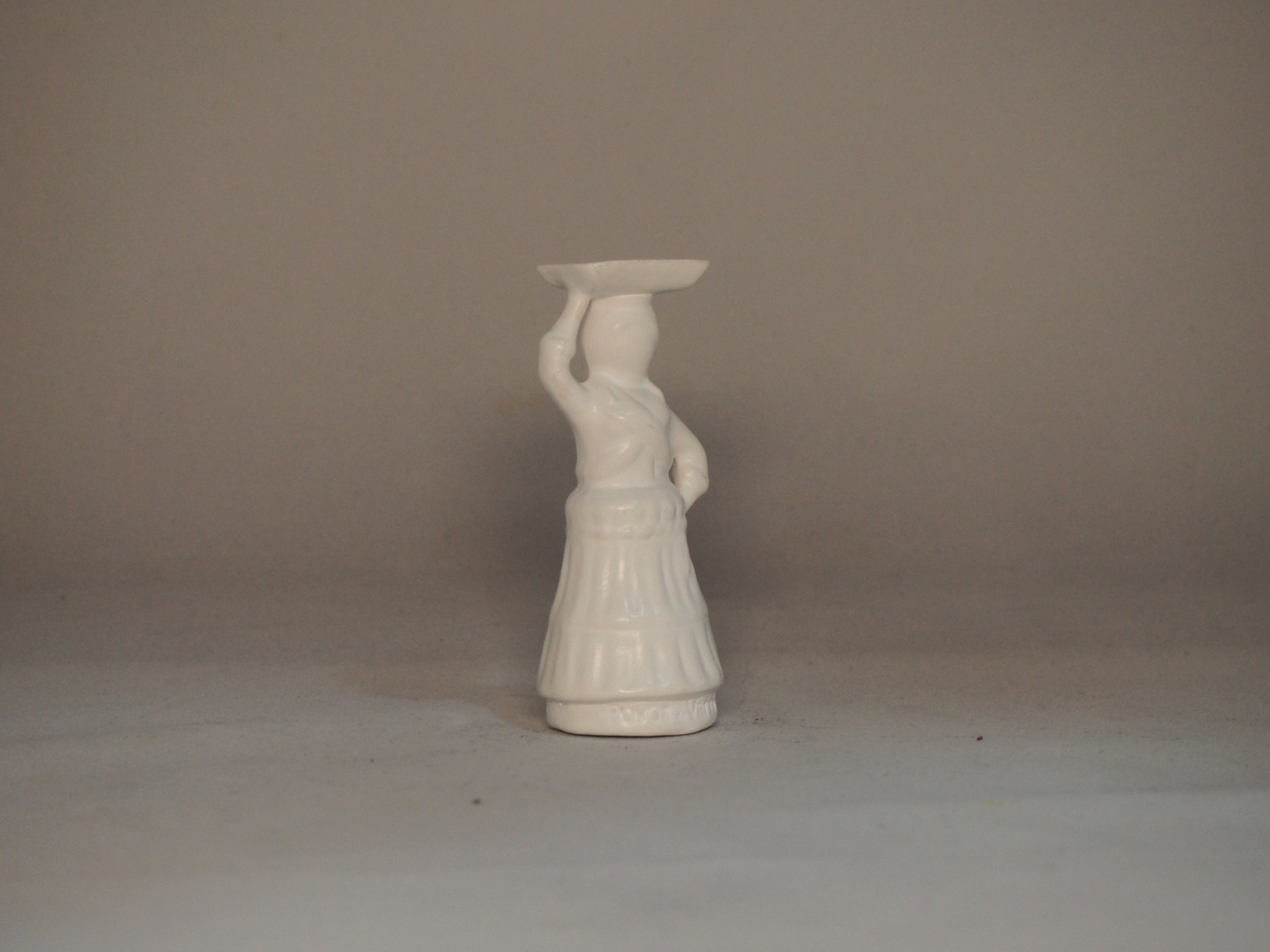 Estatueta branca de cerâmica de uma figura com prato na cabeça