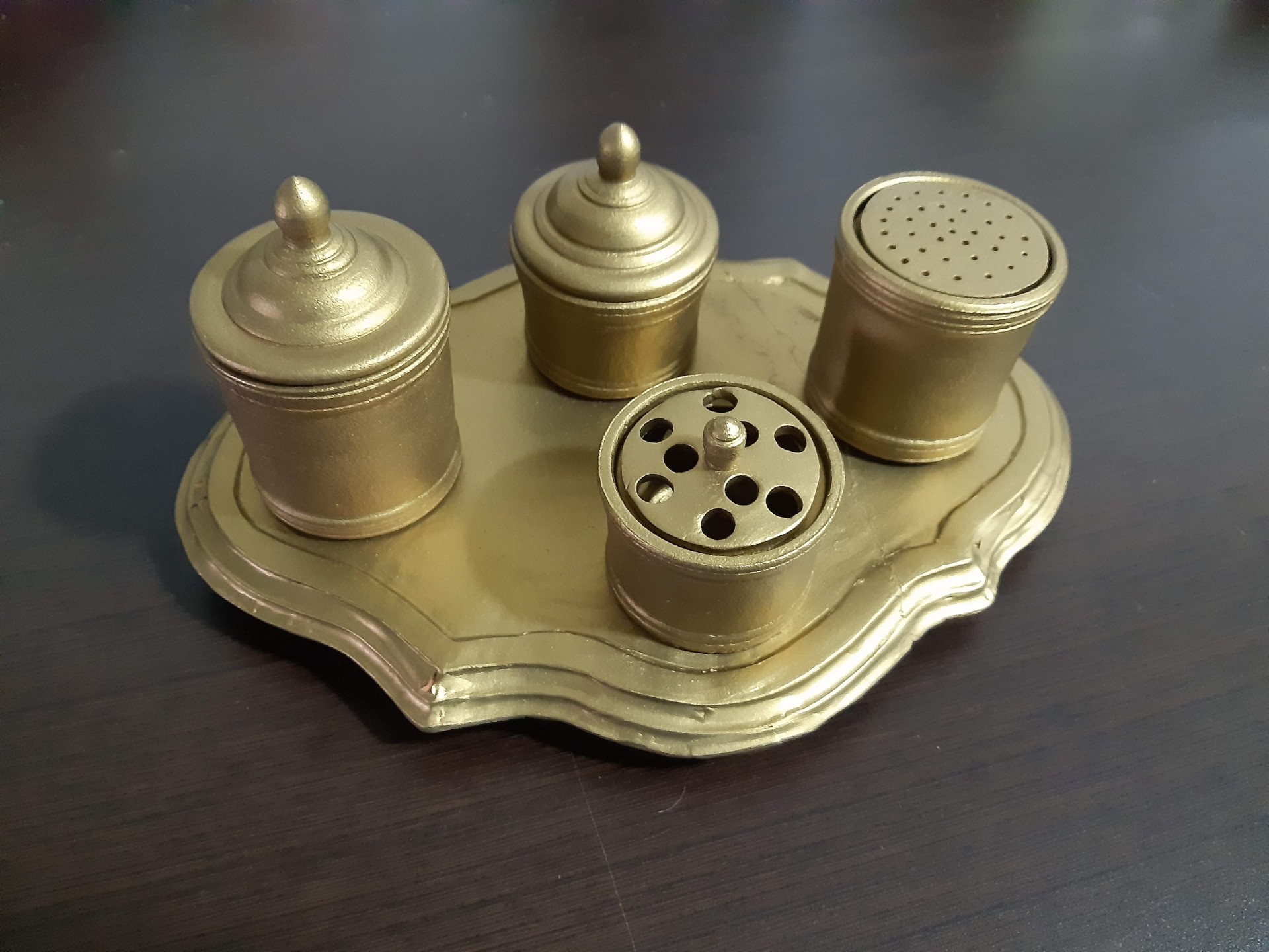 Conjunto dourado de recipientes metálicos com tampa sobre prato