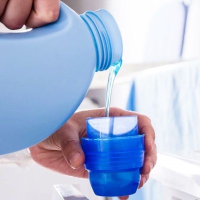 Pessoa a verter líquido azul de garrafa para copo medidor azul