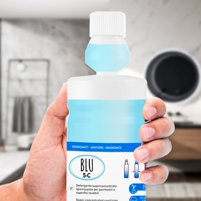 Frasco de desinfetante azul com rótulo BLU 5-C segurado por uma mão num casa de banho