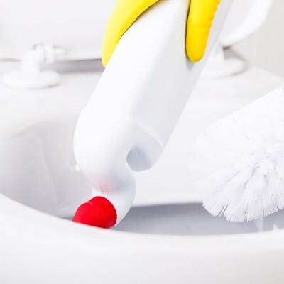 Aplicação de detergente em lavatório branco com escova de limpeza ao lado