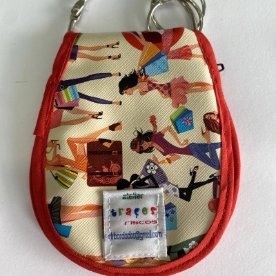 Estojo com ilustração de pessoas e sacolas, borda vermelha e etiqueta com texto