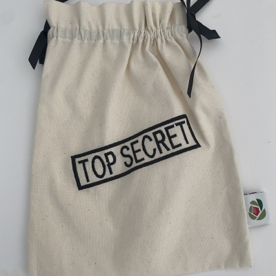 Saco de tecido cru com cordão preto e inscrição 'TOP SECRET'