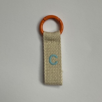 Chaveiro com argola laranja e tirante em tecido bege com letra C azul