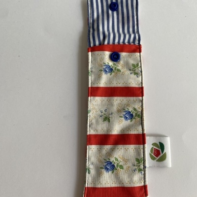 Estojo de tecido com riscas vermelhas e flores azuis, interior às riscas azuis.